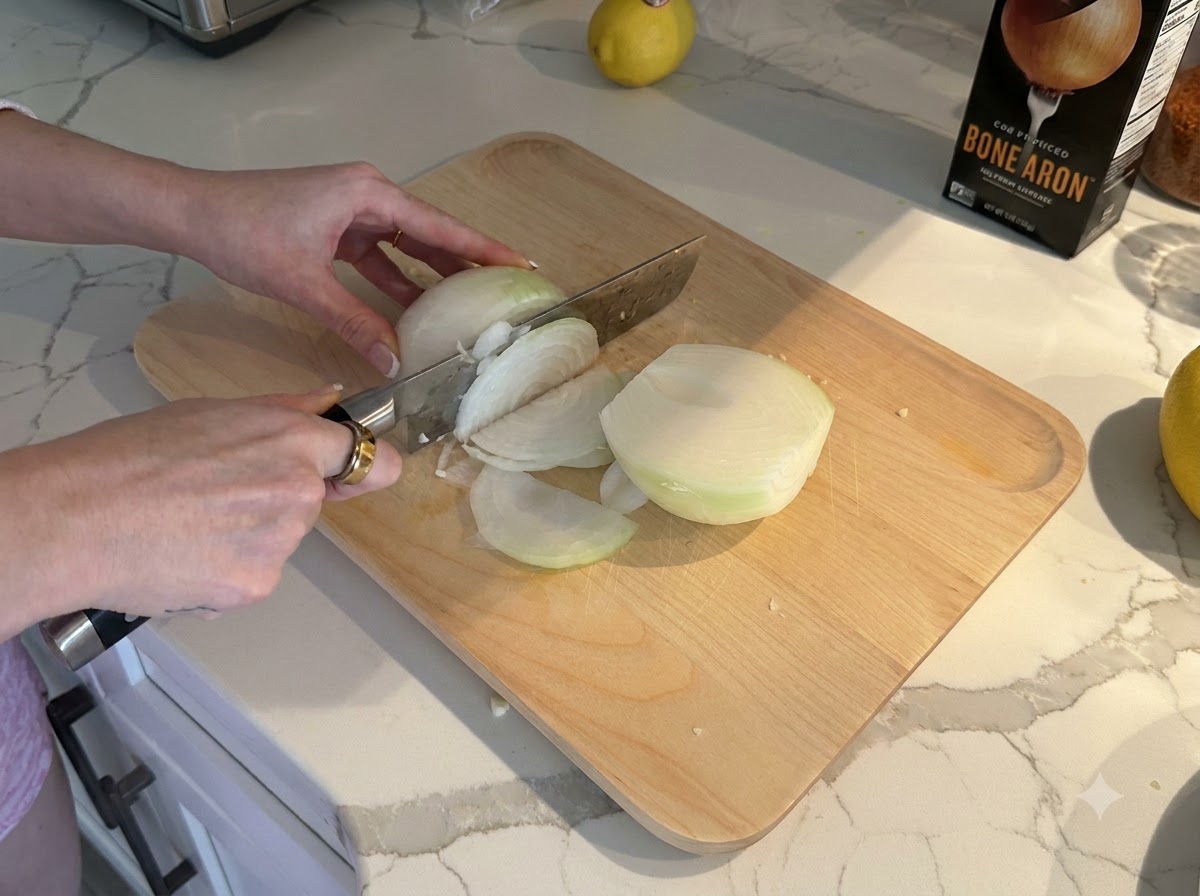 Eine weiße Zwiebel, die auf einem Holzschneidebrett in kleine Stücke geschnitten und gewürfelt wird.