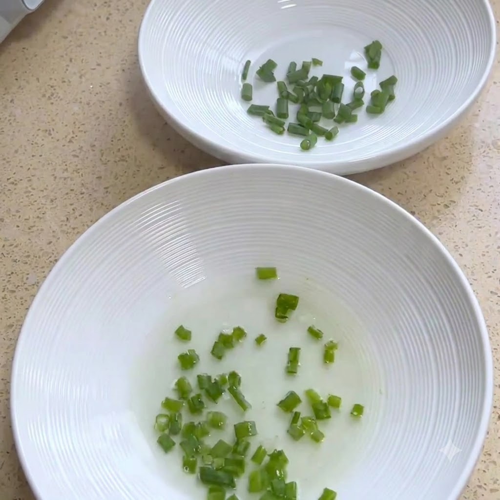 Weiße Servierschalen mit gehackten Frühlingszwiebeln.