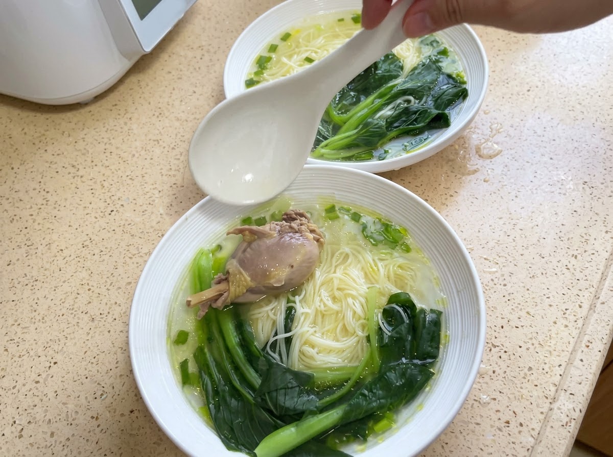 Eine Schüssel Nudeln, getoppt mit einem Stück Hähnchen und gekochtem Pak Choi.