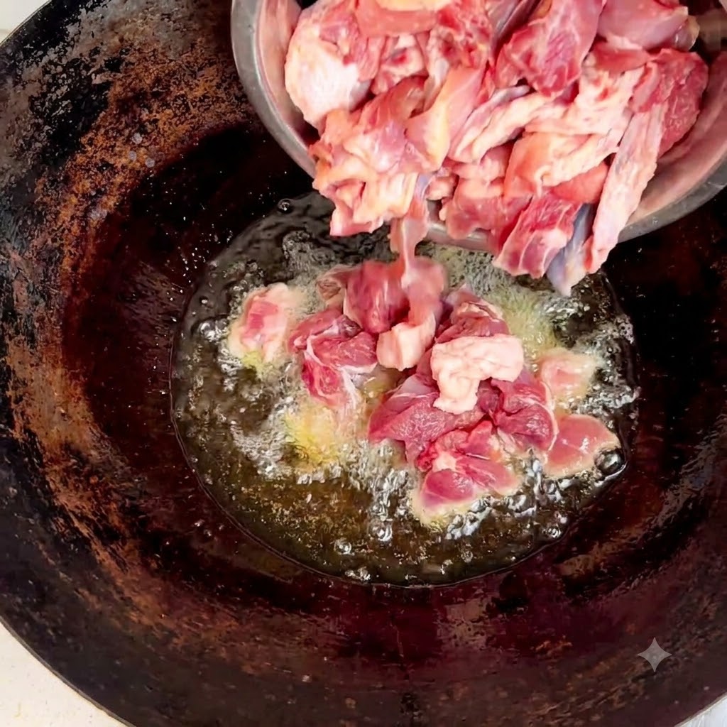 Rohe Hühnerstücke werden aus einer Stahlschüssel in den Wok mit Öl und Ingwer gegossen.