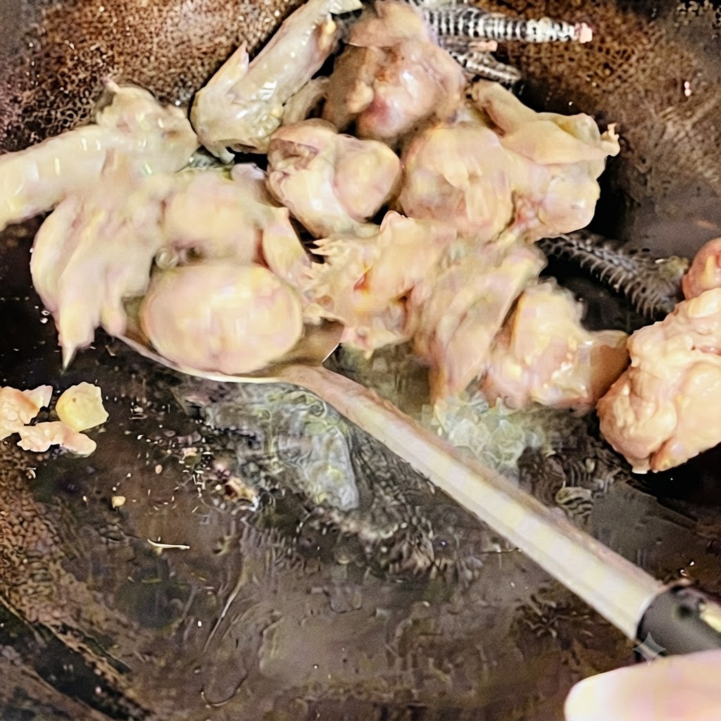Hühnerstücke werden mit einem Pfannenwender im Wok gewendet und angebraten, bis sie leicht gebräunt sind.