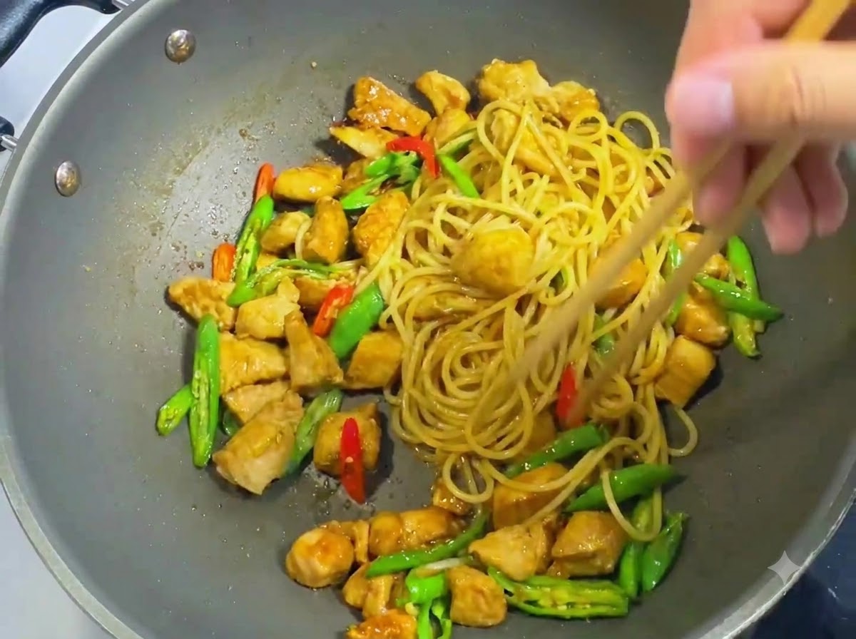 Holzessstäbchen vermengen und wenden Spaghetti-Nudeln, gewürfeltes Hähnchen, geschnittene Chilis und dunkle Soße gleichmäßig in einem Wok.