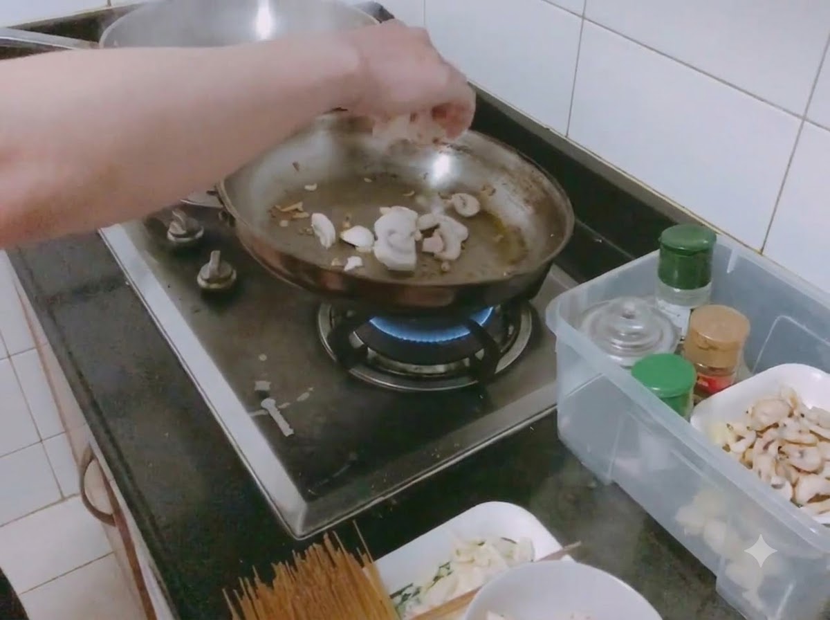Geschnittene weiße Champignons und gewürfelte Zwiebeln werden mit Salz in einer Bratpfanne sautiert.