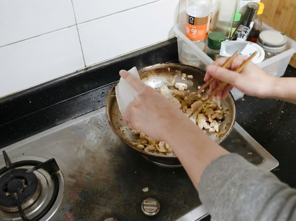 Gekochte Hähnchenstreifen werden wieder in die Pfanne zu Champignons und Zwiebeln gegeben.