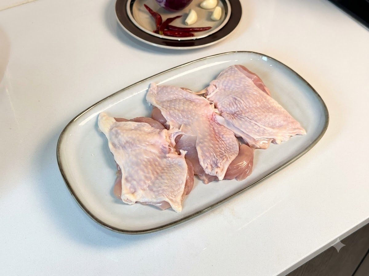 Knochenlose Hähnchenschenkel auf einem weißen rechteckigen Teller, bestäubt mit schwarzem Pfeffer und Gewürzen.