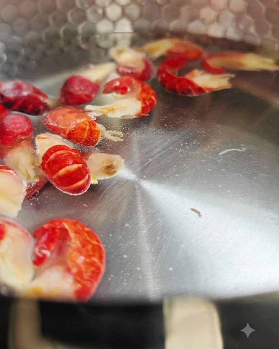 Gefrorene Flusskrebsschwänze kochen in einem Metalltopf mit heißem Wasser.