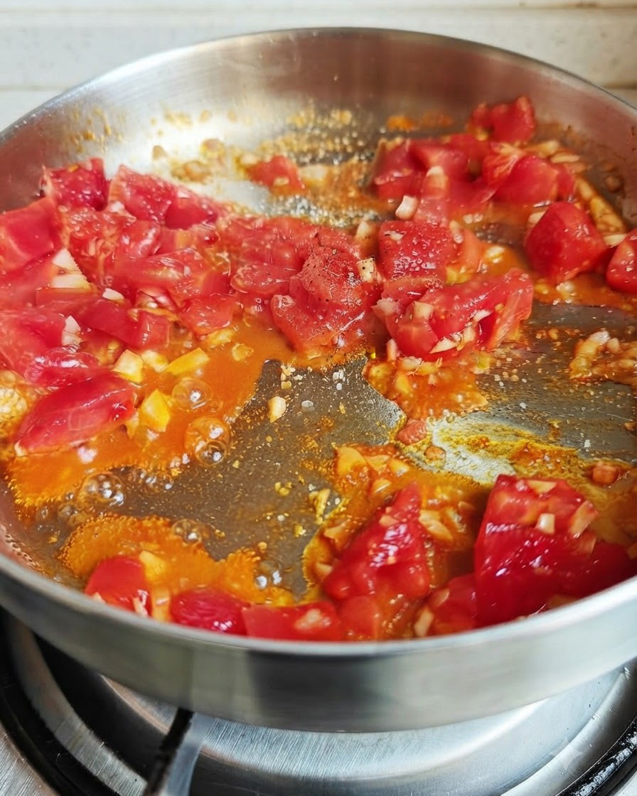 Tomaten kochen in einer Pfanne mit gestreuten Gewürzen wie Salz, Pfeffer und Sojasoße.