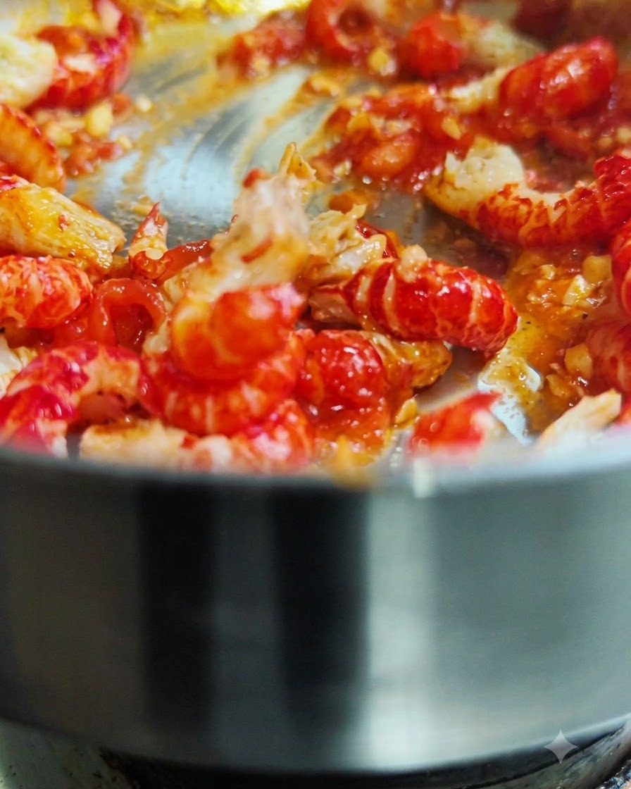 Geschälte Flusskrebsschwänze werden in einer heißen Pfanne mit roter Tomatensoße geschwenkt und angebraten.