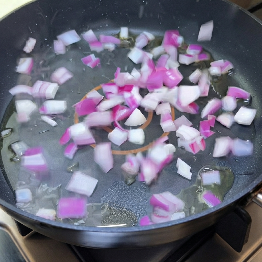 Gewürfelte rote Zwiebel brutzelt in Öl in einer Bratpfanne.