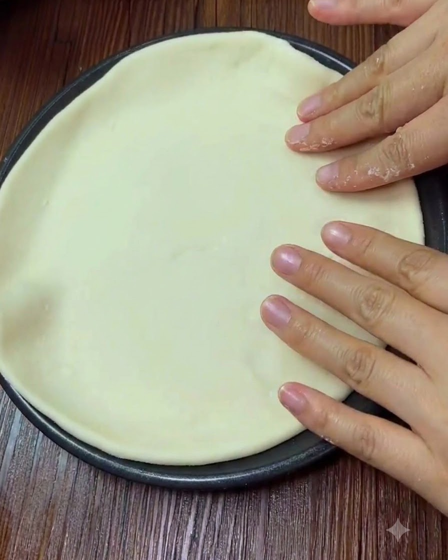Hände drücken vorsichtig auf die Oberfläche des ausgebreiteten Pizzateigs.