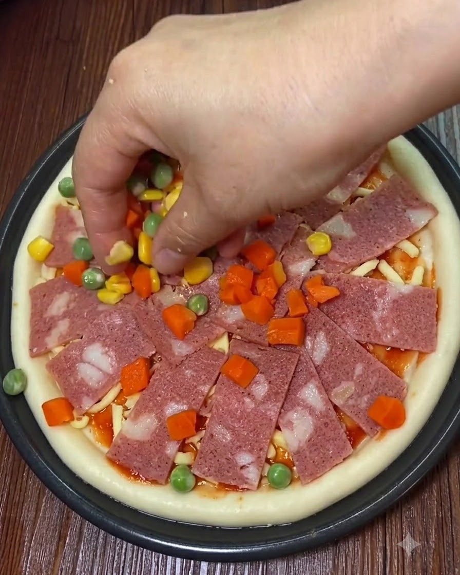 Speckscheiben, süßer Mais und gewürfeltes Gemüse werden auf die Pizza gelegt.