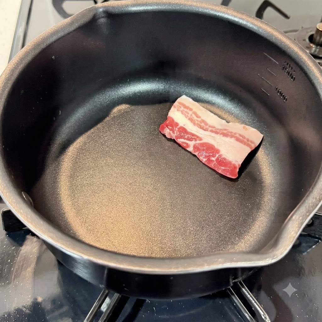 Rohe Schweinebauchscheiben in einem leeren schwarzen Kochtopf ausgelegt.