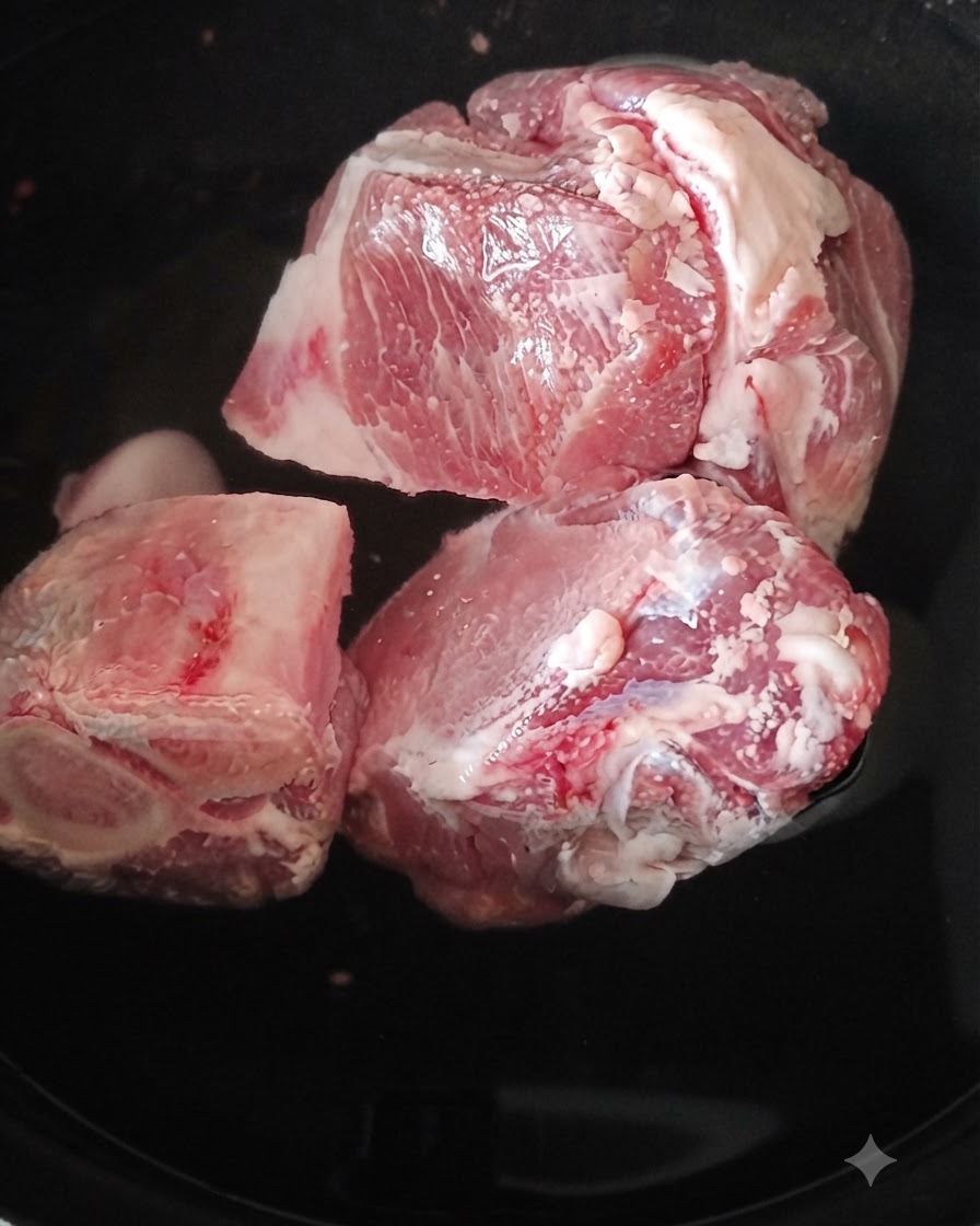 Nahaufnahme von blanchierten Schweinebeinknochen, die mit heißem Wasser abgespült werden.