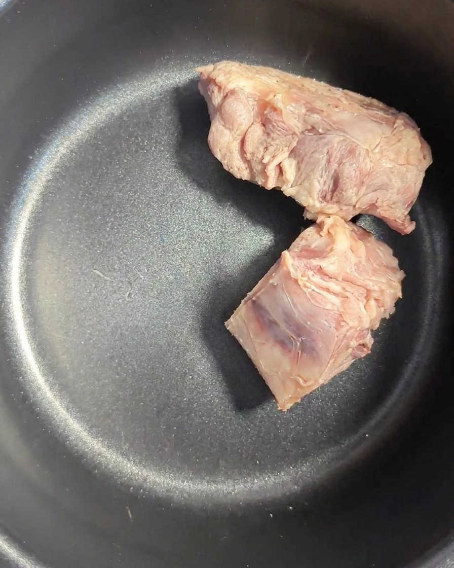 Gereinigte Schweineknochen in einem dunklen Reiskochertopf.