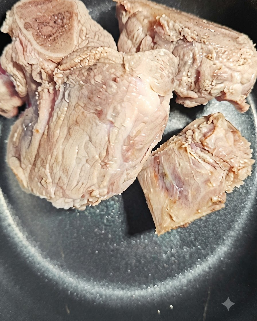 Eine Scheibe Angelikawurzel neben den Schweineknochen im Topf.