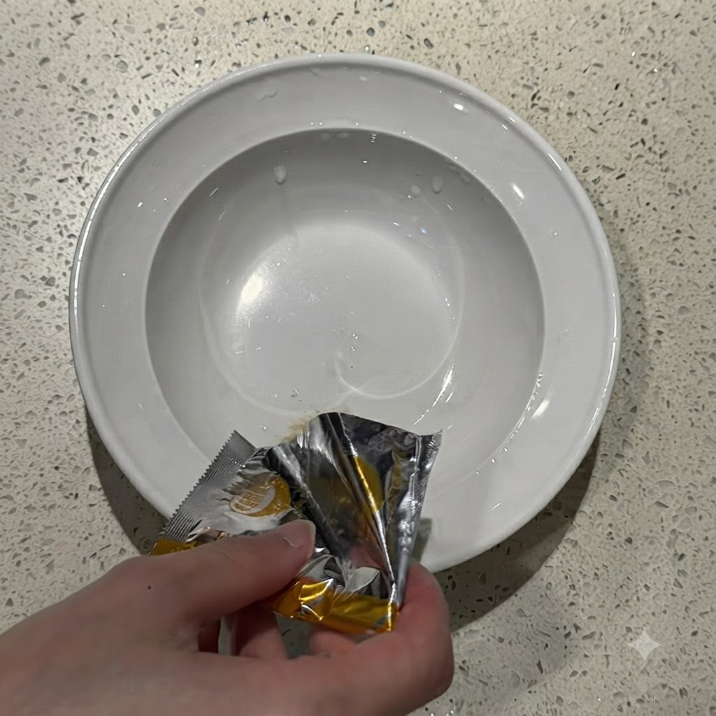 Instant-Ramen-Gewürzpulver wird aus einer silbernen Tüte in den Boden einer weißen Keramoschale geschüttet.