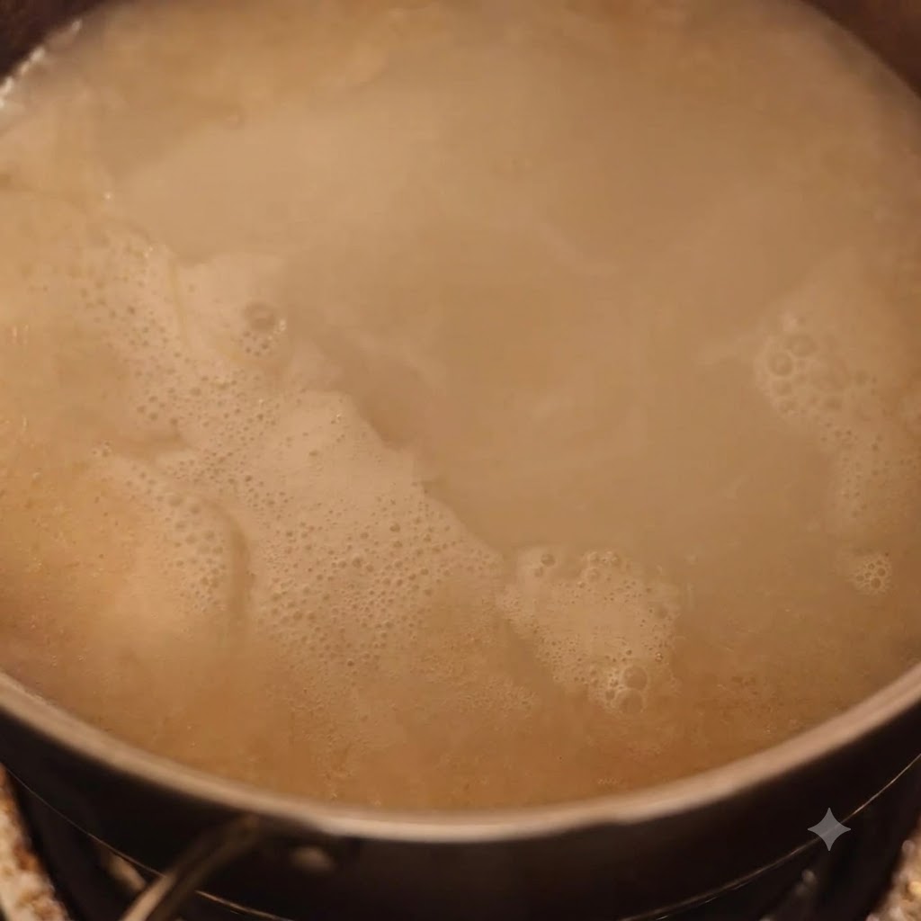 Zerstampftes Fleisch wird in eine köchelnde Tonkotsu-Brühe eingerührt.