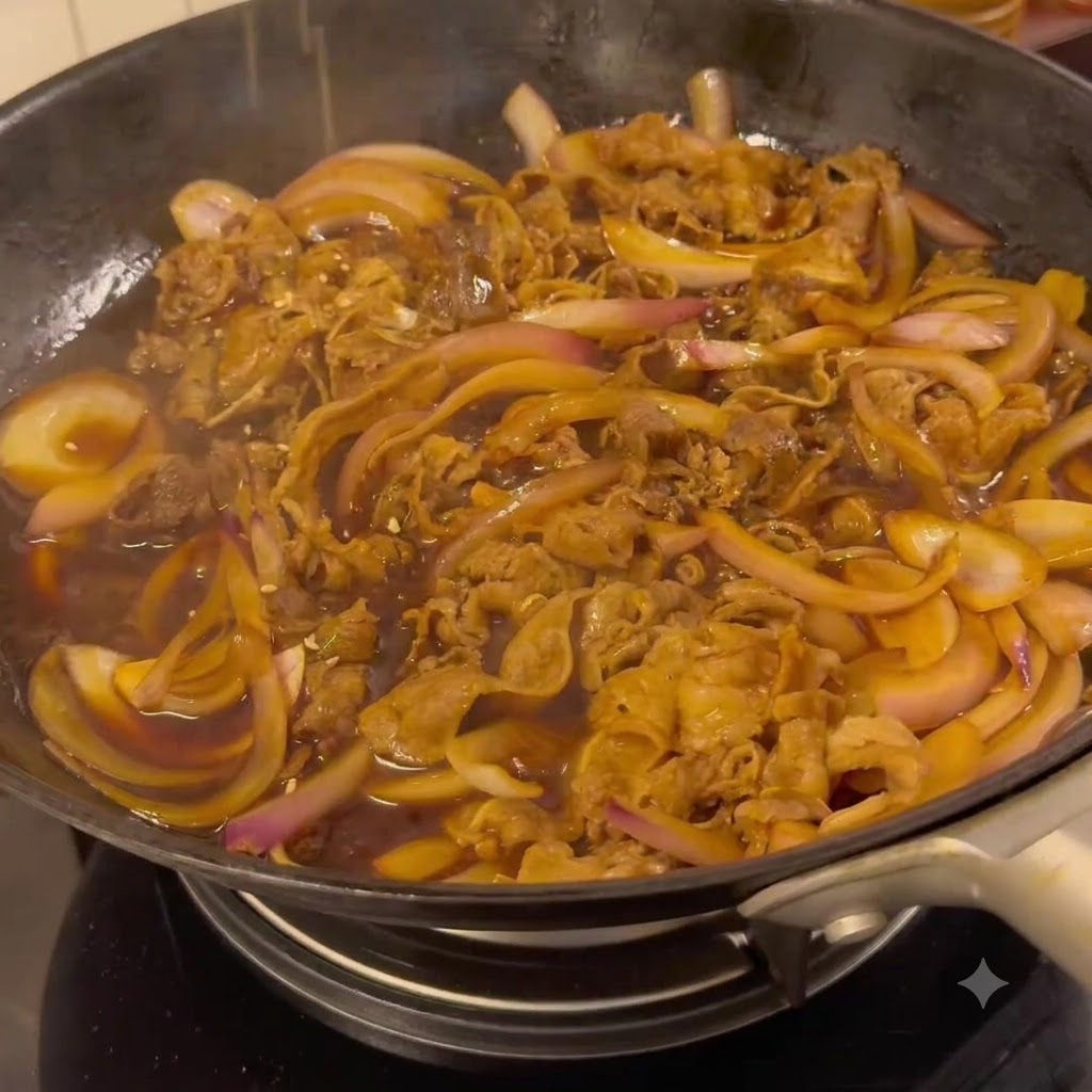 Rindfleisch und Zwiebeln köcheln in einer dunklen Teriyaki-Sauce in einer Bratpfanne.