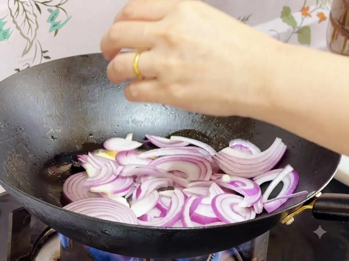 In geschmolzener Butter im Wok angebratene rote Zwiebelstreifen.