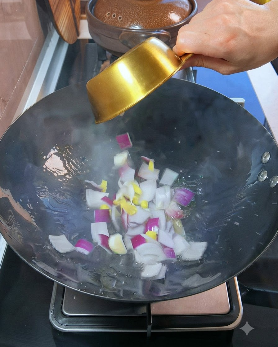 Gewürfelte rote Zwiebeln und Knoblauch werden aus einer kleinen goldenen Schüssel in den Wok mit heißem Öl gegeben.