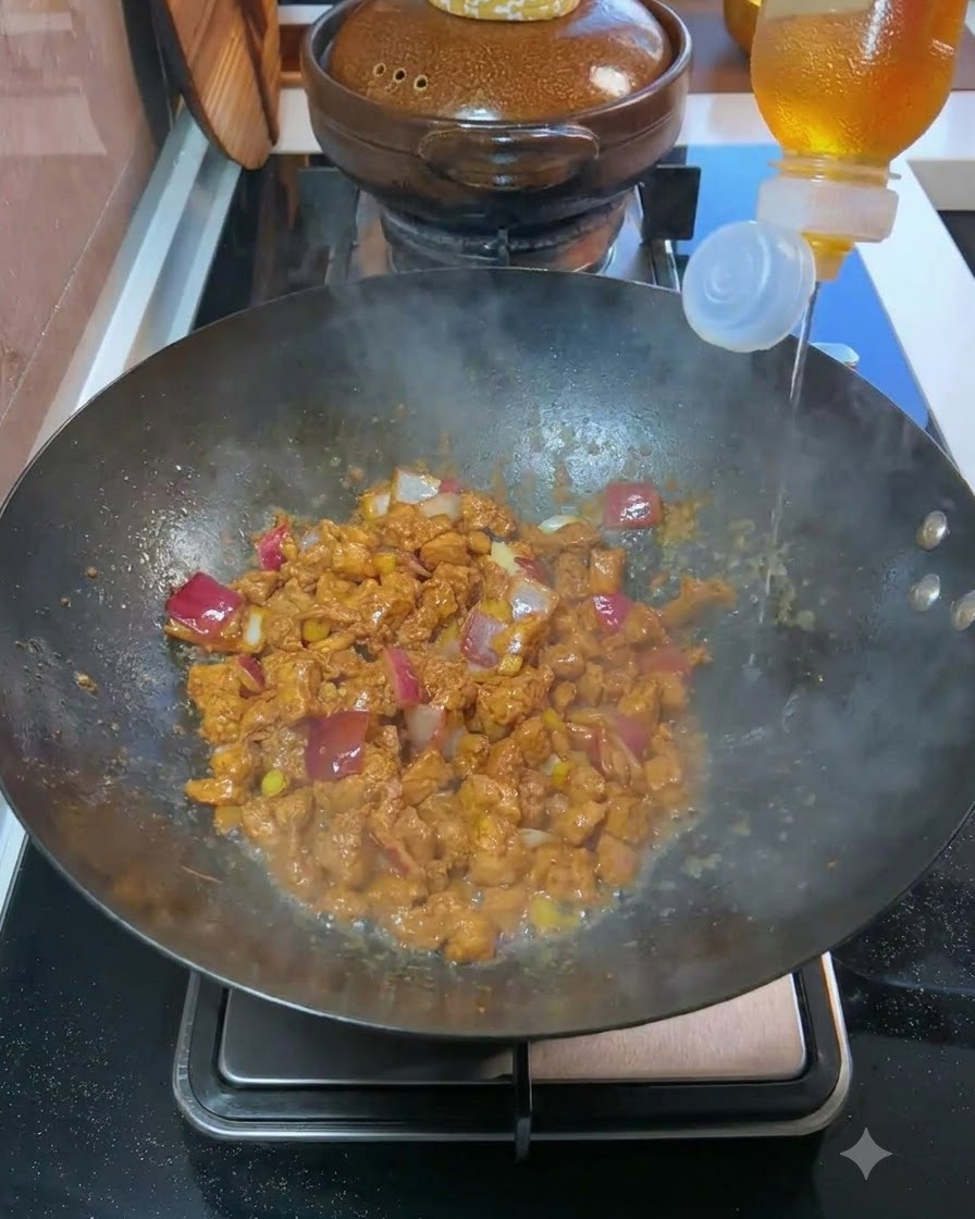 Kochwein wird aus einer Flasche in einen Wok mit gegartem Fleisch und gewürfelten Zwiebeln gegossen.