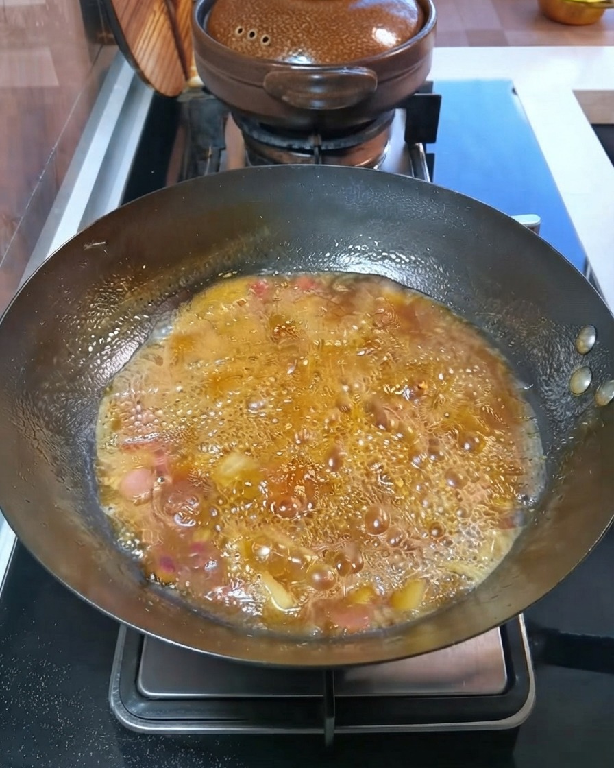 Gewürfelte Kartoffeln und Karotten köcheln in einer blubbernden Brühe im Wok.