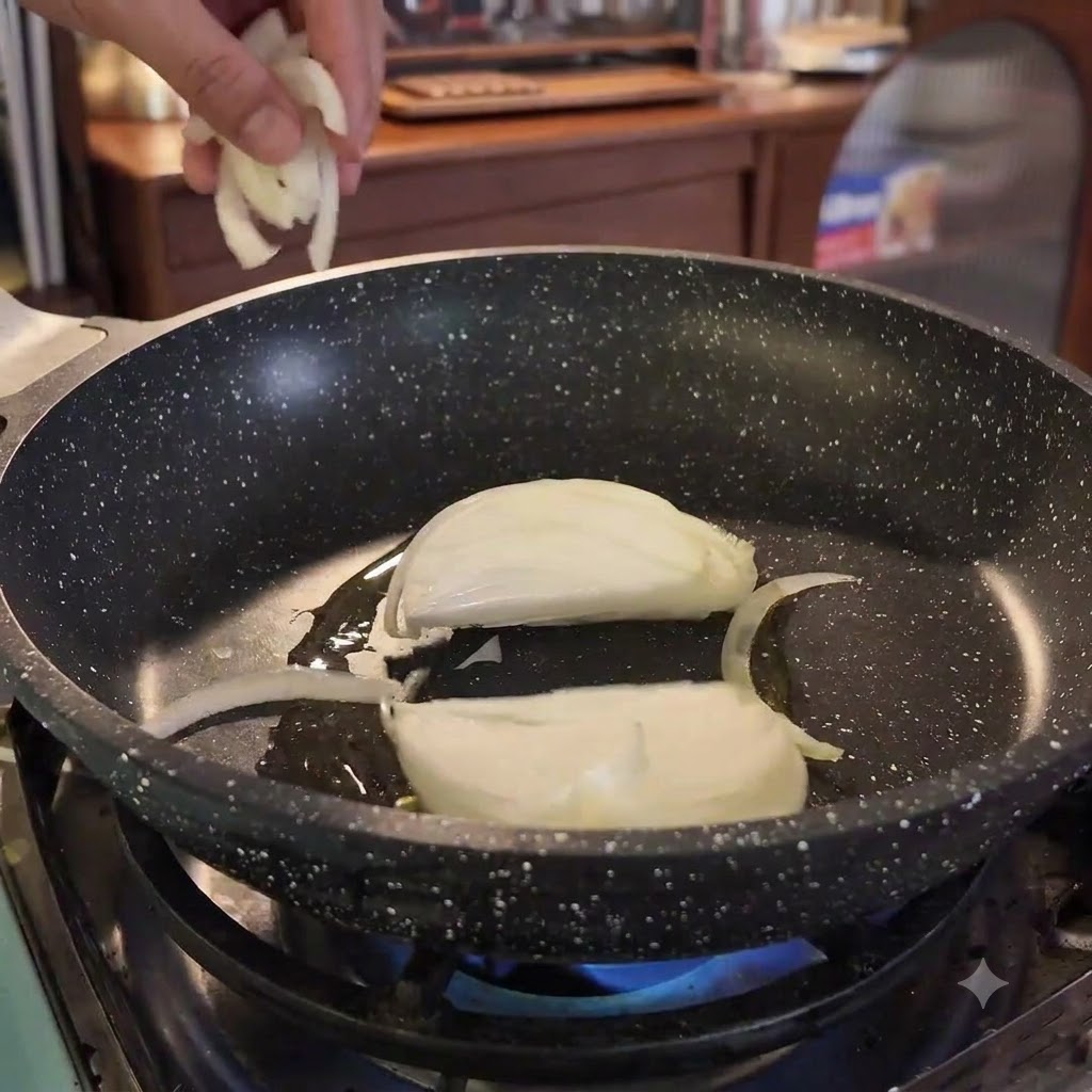Zwiebelstreifen werden in eine heiße Pfanne mit Öl über einer blauen Flamme gegeben.