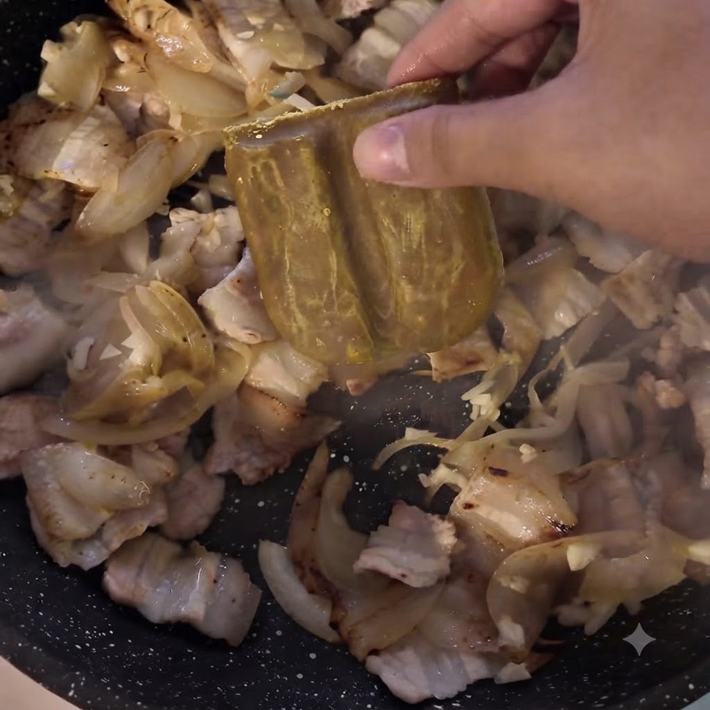Ein Currypaste-Block wird in die Pfanne mit Fleisch und Zwiebeln gegeben.