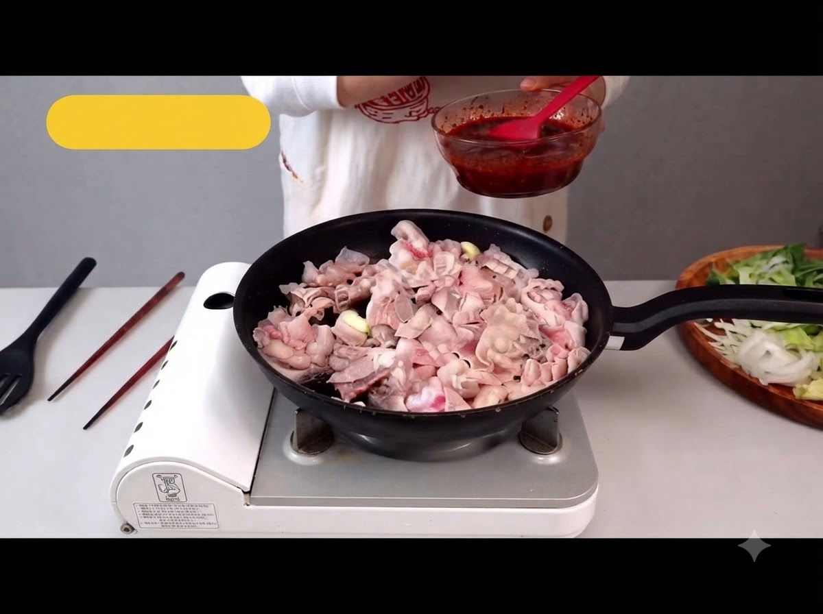 Dünn geschnittener Schweinebauch brät in einer Pfanne, wobei das Fett langsam austritt.