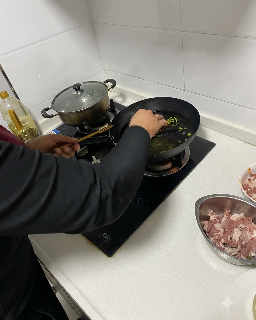 Gehackte Aromen werden mit Essstäbchen in das heiße Öl im Wok gegeben.