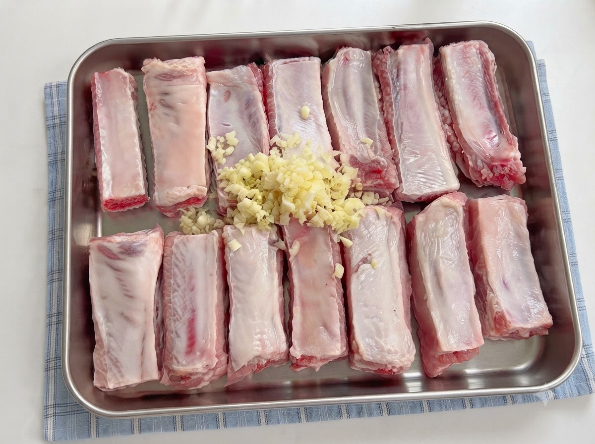 Saucen werden mit einem Löffel über die gewürzten Schweinerippchen mit Knoblauch gegossen.