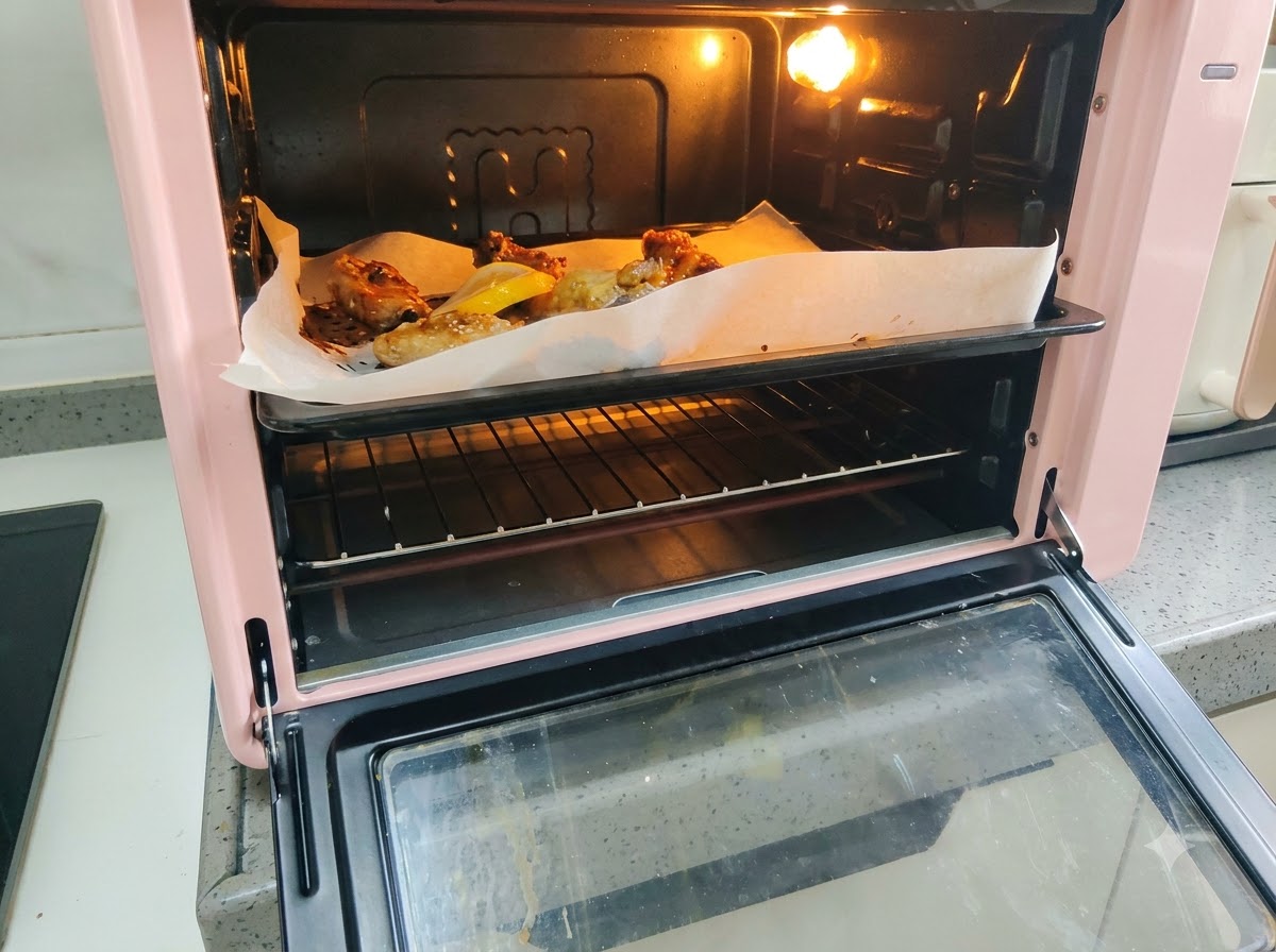 Frische Zitronenscheiben, die neben den bratenden Schweinerippchen auf dem Backblech angeordnet sind.