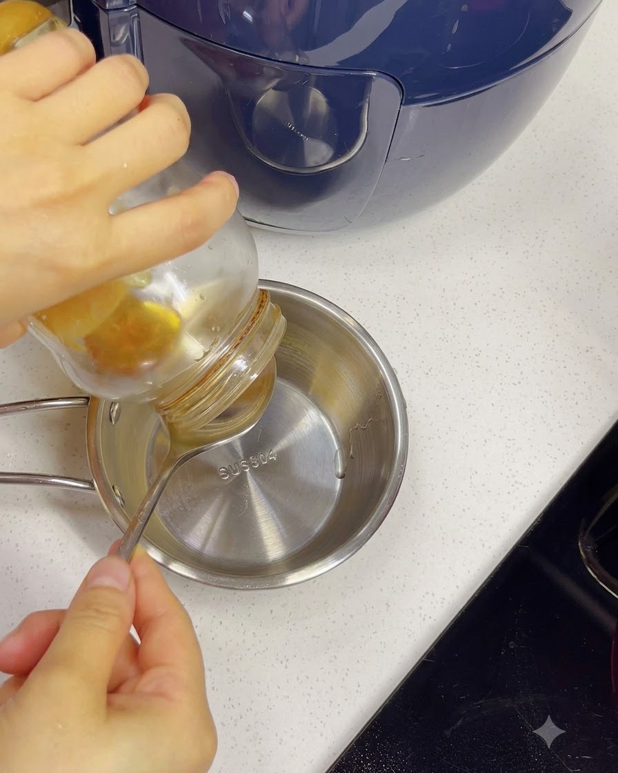 Honig wird aus einem Glas mit einem Löffel in eine kleine Edelstahl-Schüssel mit Wasser gegossen.