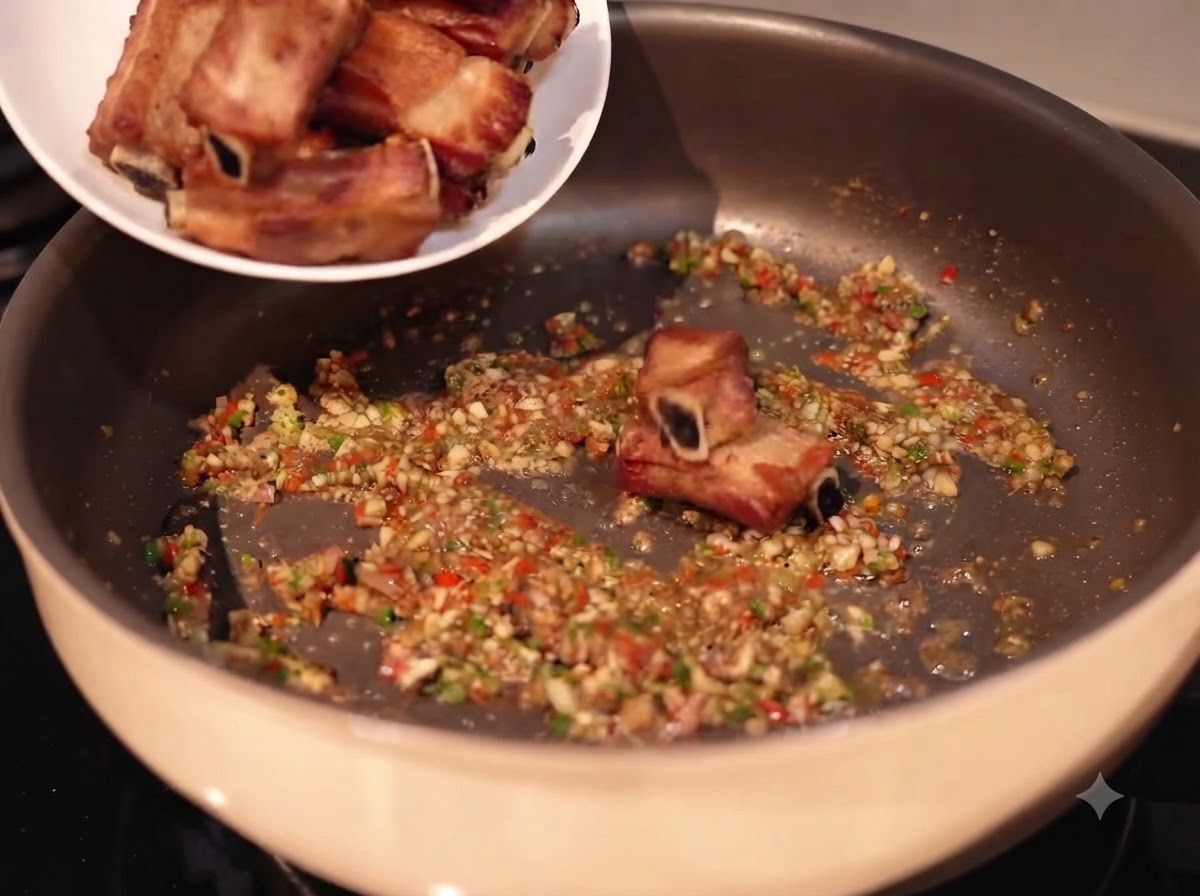 Spare Ribs werden von einem weißen Teller in eine Pfanne mit gehacktem Knoblauch, Chilis und Gewürzen gegebencite: 1.