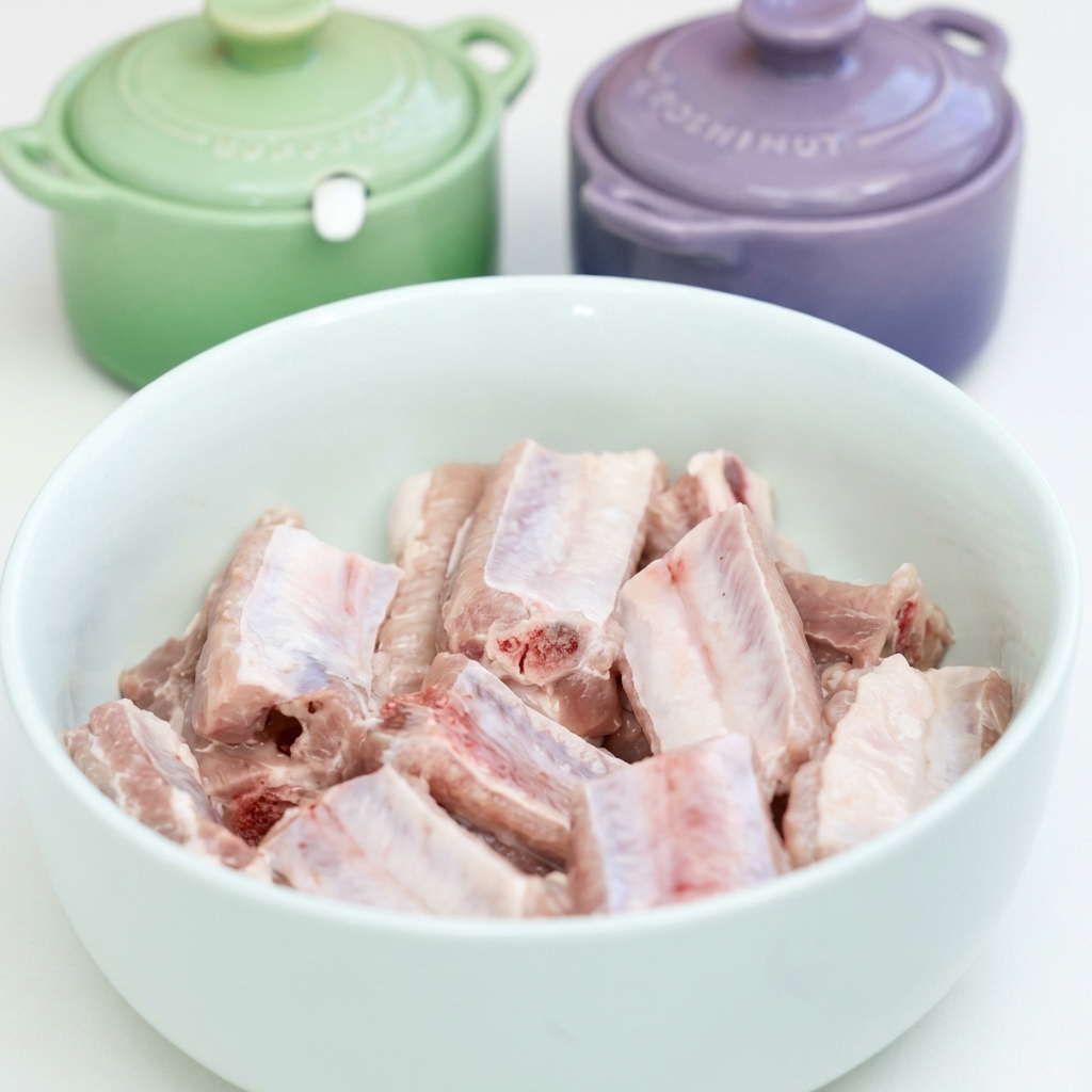 Rohe Schweinerippchen in einer weißen Schüssel werden mit Knoblauch, Sojasaucen, Austernsauce und Gewürzen mariniert.