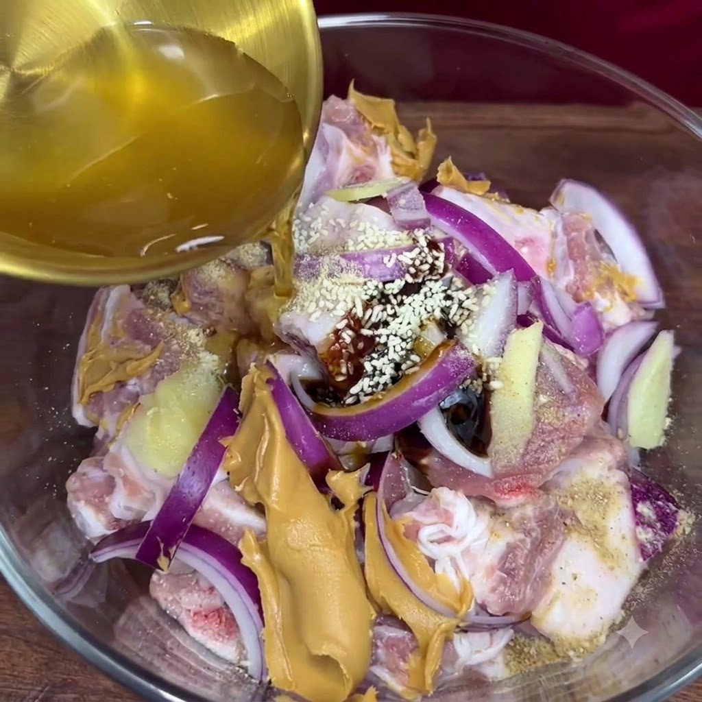 Goldener Knoblauchsaft wird aus einer Schöpfkelle in die Glasschüssel mit den gewürzten Schweinerippchen und anderen Marinadezutaten gegossen.