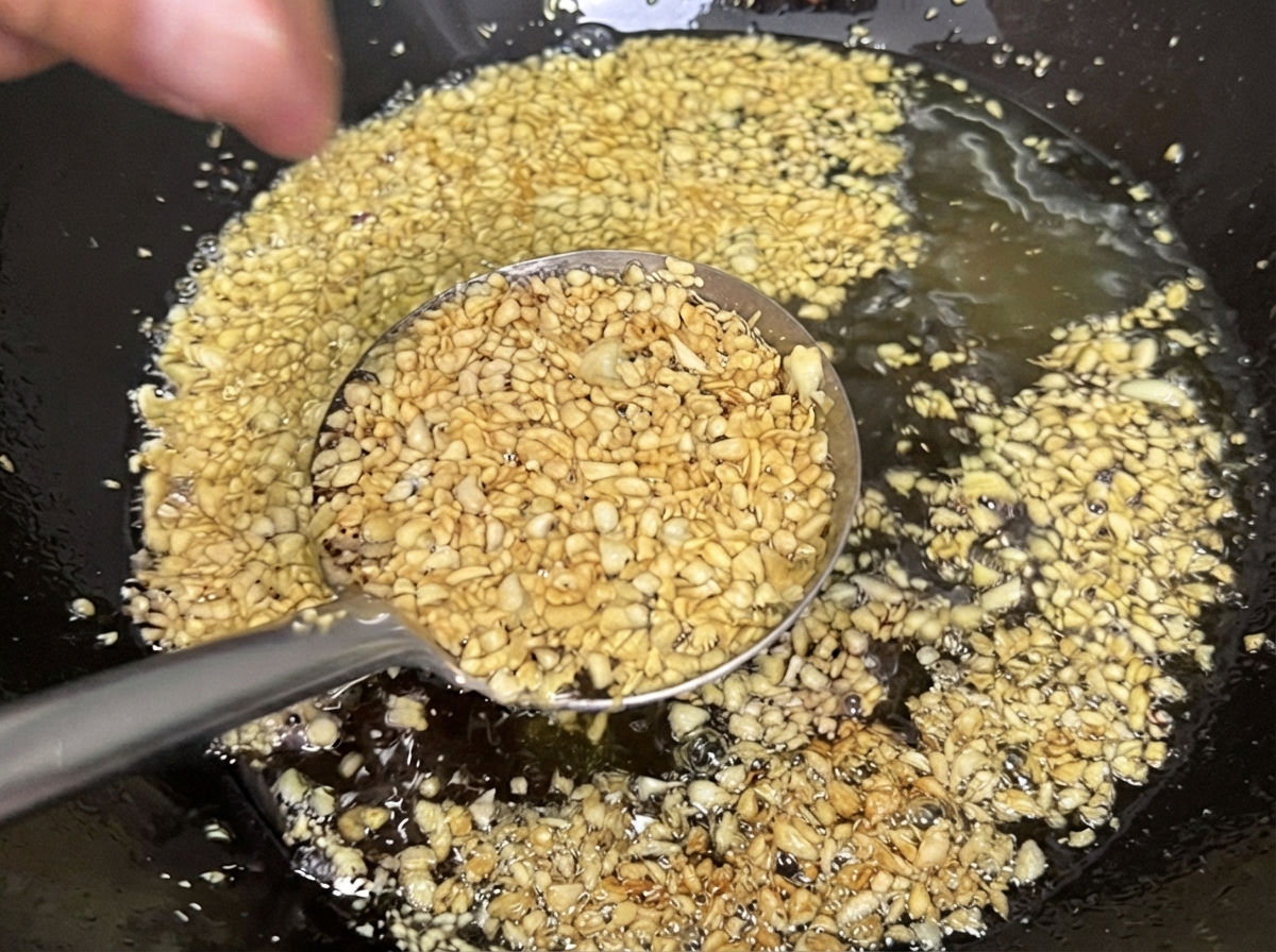 Hackknoblauch frittiert in Öl in einem Wok und färbt sich hell goldgelb und knusprig.