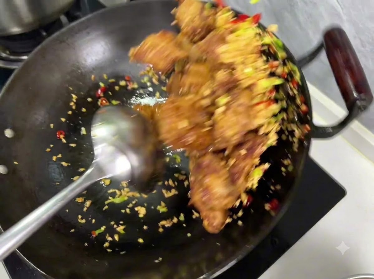 Salz- und Pfeffergewürz wird über die Mischung aus Rippchen und Knoblauch in einem Wok gestreut.