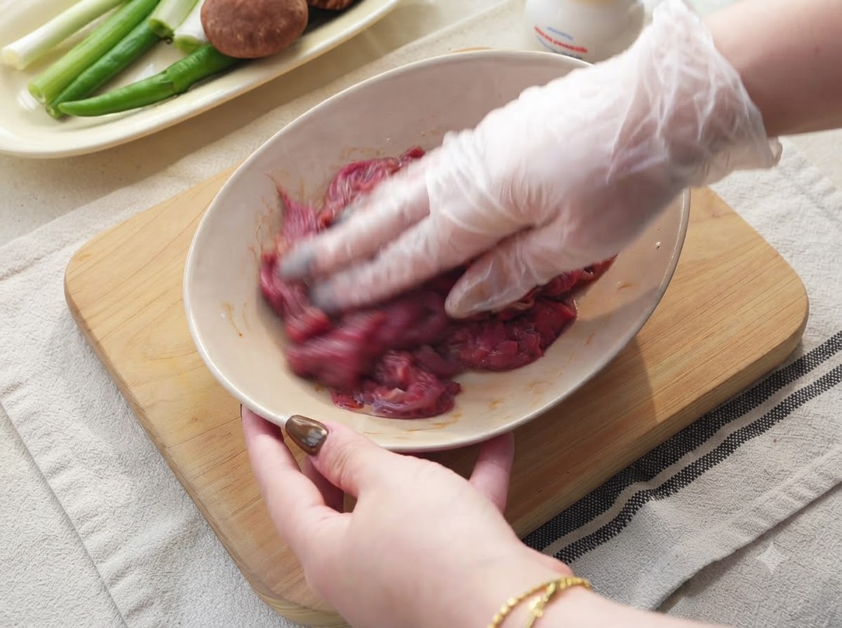 Zwiebeln, grüne Chilis und Knoblauch werden auf einem Holzschneidebrett in Scheiben geschnitten.