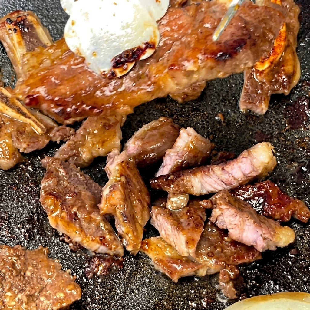 Eine Zonge hält ein gekochtes Short Rib, während eine Schere es in Stücke schneidet.