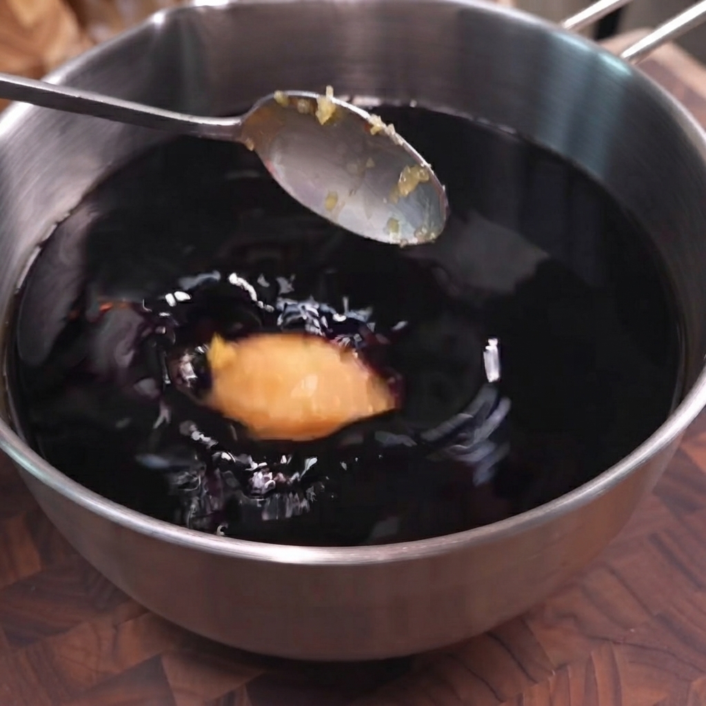 Ein Löffel gehackter Knoblauch wird in einen Topf mit dunkler Sojasaucen-Marinade gegeben.