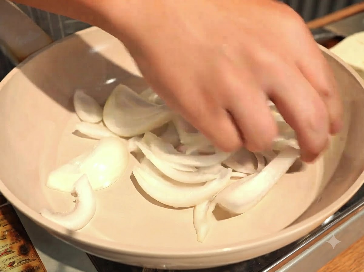 Das gleichmäßige Verteilen der geschnittenen Zwiebeln auf dem Boden einer flachen Kochpfanne.
