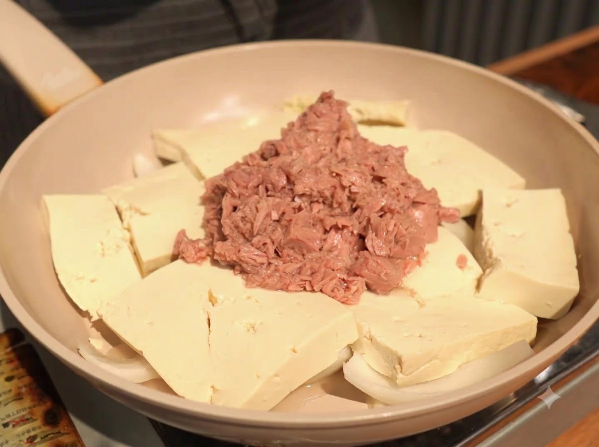 Das Hinzufügen einer Löffelspitze Knoblauchpaste auf den Tofu neben dem Thunfisch.
