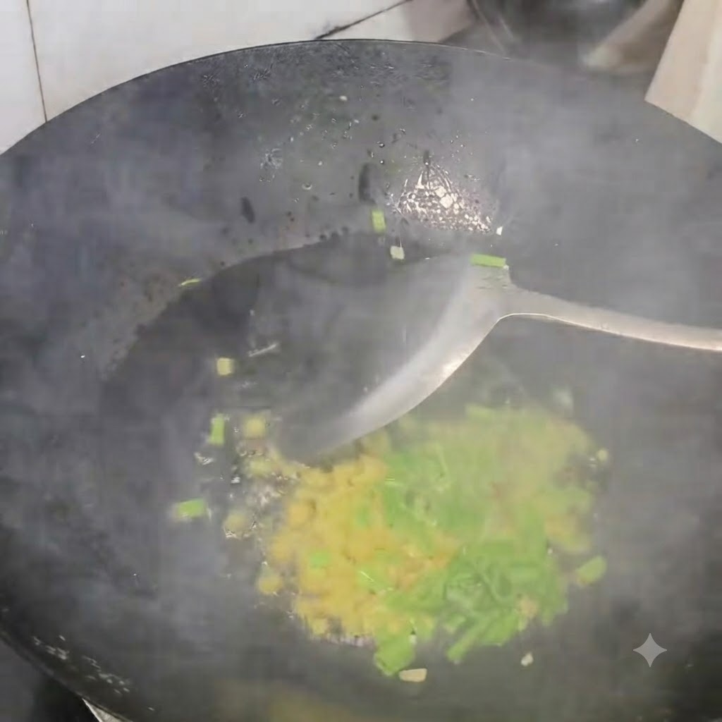 Gehackte Frühlingszwiebeln, Ingwer und Knoblauch werden in einem heißen schwarzen Wok mit einem Pfannenwender angebraten.