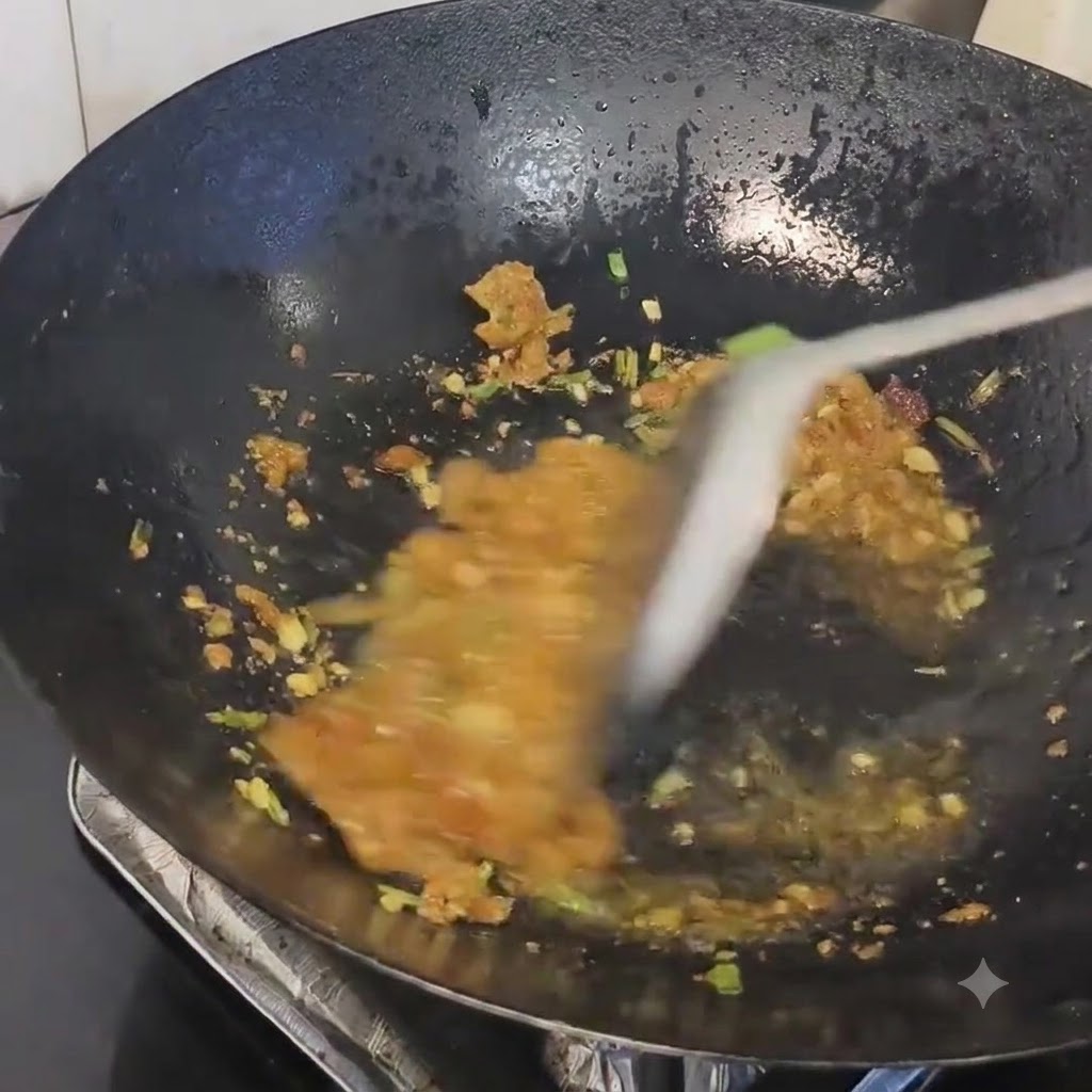 Schweineschmalz-Rückstände werden in einem heißen Wok unter die angebratenen Aromen gemischt.