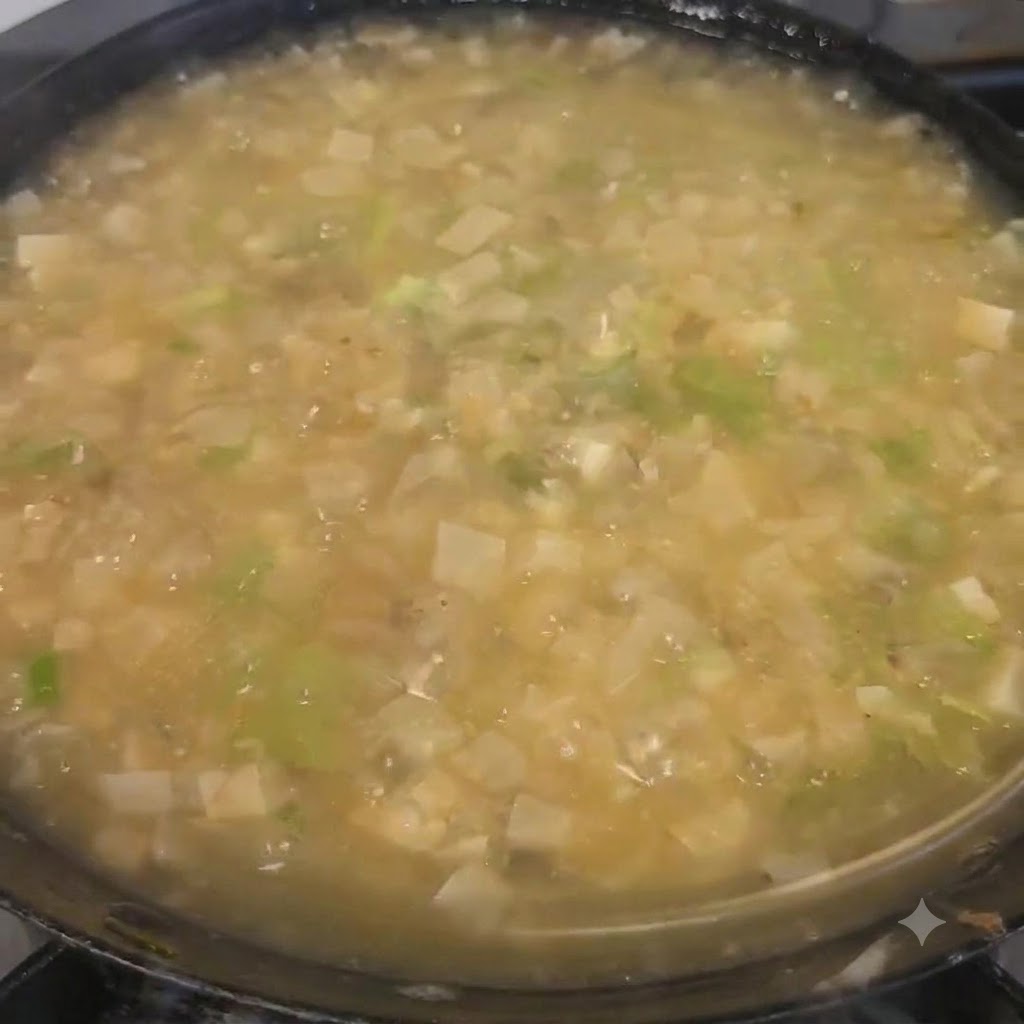 Gehackter Koriander wird über die fertige Suppe im Topf gestreut.