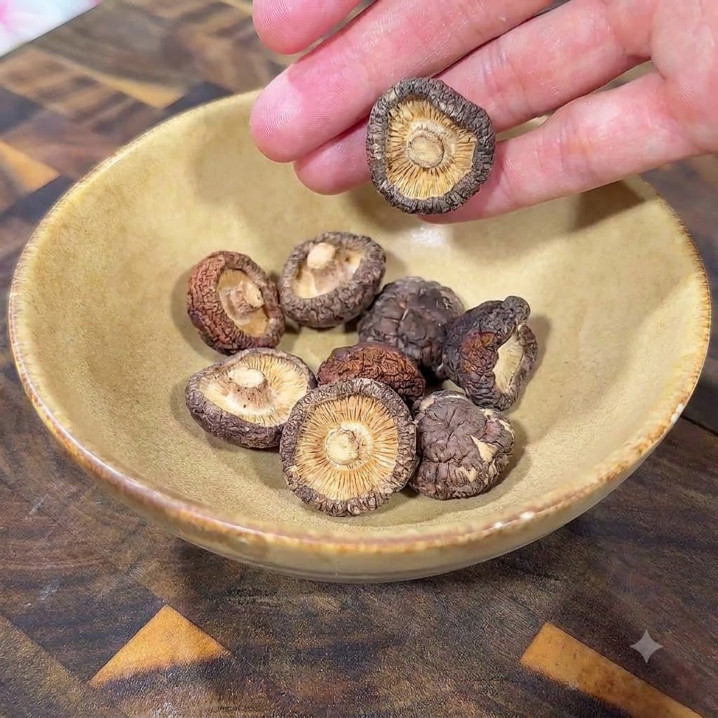 Getrocknete Shiitake-Pilze in einer gelben Keramikschüssel auf einer Holzoberfläche.