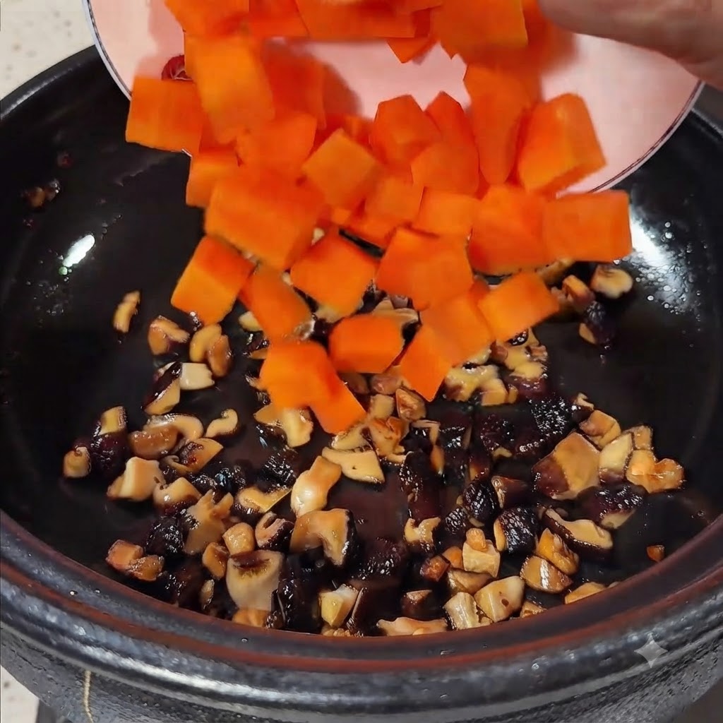 Leuchtend orange gewürfelte Karotten werden von einem Teller in den Topf mit den angebratenen Pilzen gegeben.