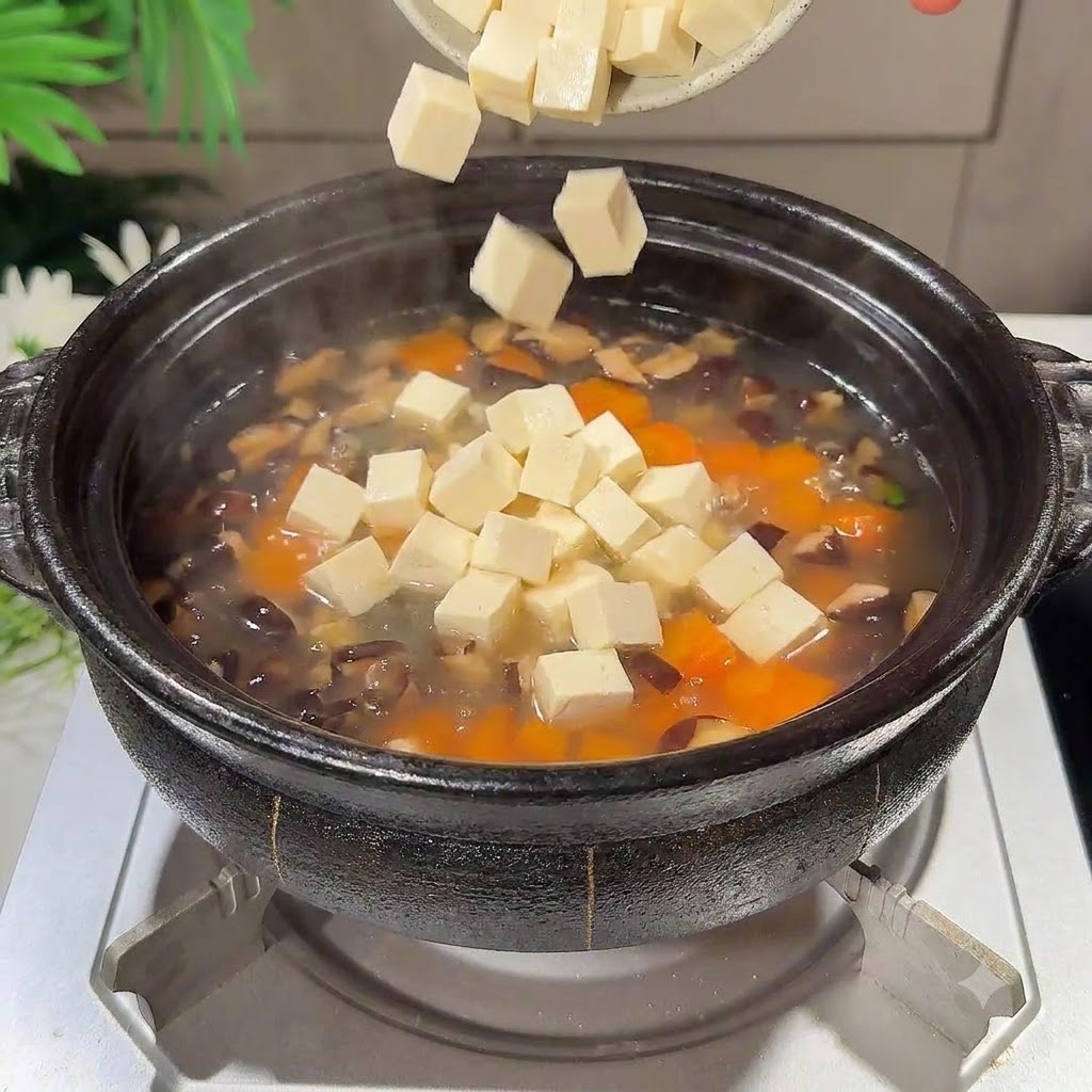Gewürfelte Seidentofustücke fallen in den köchelnden Suppentopf.