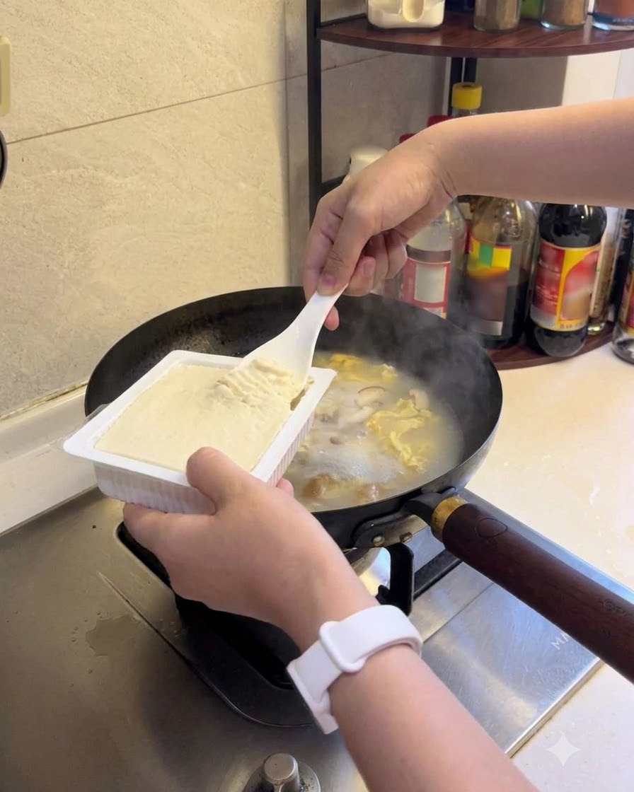 Weicher Tofu wird in die köchelnde Suppe gegeben.